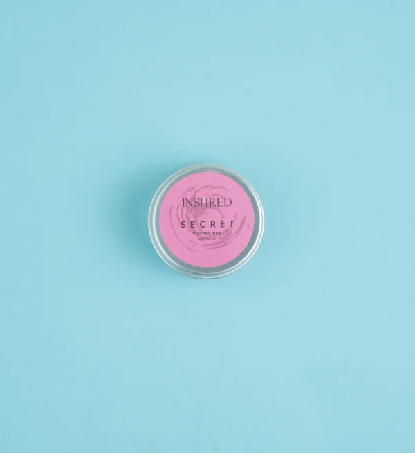 Collection of Solid Perfume Secret tins arranged stylishly, highlighting affordable luxury alternatives to Bombshell.